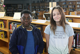  A boy and a girl stand next to each other in a library